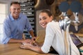 Smiling manager and bartender standing at bar counter