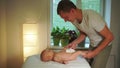 Smiling masseur plays with little boy shaking toddler legs