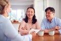 Smiling Mature Asian Couple At Home Meeting With Female Healthcare Worker In Mask During Pandemic Royalty Free Stock Photo