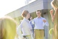 Smiling mature business colleagues talking while standing by railing at rooftop during success party Royalty Free Stock Photo