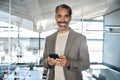 Smiling mature business man executive using phone standing in office. Portrait. Royalty Free Stock Photo