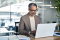 Smiling middle aged business man executive sitting at desk using laptop. Royalty Free Stock Photo