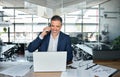 Smiling mature business man talking on cell phone using laptop in office. Royalty Free Stock Photo