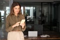 Smiling mature business woman holding smartphone standing in corporate office. Royalty Free Stock Photo