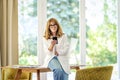 Smiling mature business woman sitting at desk and holding a mobile phone in her hand Royalty Free Stock Photo