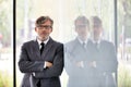 Portrait of smiling mature businessman with arms crossed leaning on wall at office Royalty Free Stock Photo