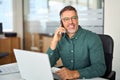 Smiling mature businessman making call on cellphone working in office. Royalty Free Stock Photo