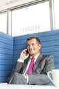 Smiling mature businessman talking on cell phone in office Royalty Free Stock Photo