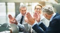 Smiling mature businesspeople clapping together in an office Royalty Free Stock Photo