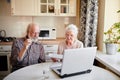 Smiling mature couple with documents and laptop in home interior Royalty Free Stock Photo