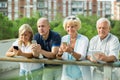 Smiling mature couples using gadgets in park Royalty Free Stock Photo