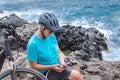 Smiling mature cyclist woman enjoying healthy activity at sea with her electro bike. Using mobile phone