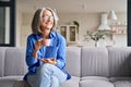 Senior smiling 60s woman portrait at home looking away with cup of tea, coffee.