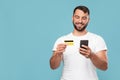 Smiling mature european guy buying goods and paying money using credit card and smartphone