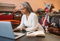 Mature woman working on a laptop in her textiles store Royalty Free Stock Photo