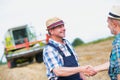 Smiling mature farmer shaking hands with senior famer in field Royalty Free Stock Photo