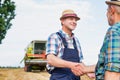 Smiling mature farmer shaking hands with senior famer in field Royalty Free Stock Photo