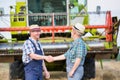 Smiling mature farmer shaking hands with senior famer in field Royalty Free Stock Photo