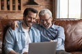 Smiling mature father and grownup son use laptop at home Royalty Free Stock Photo