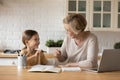 Smiling grandmother help granddaughter with homework assignment