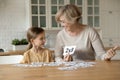 Smiling mature grandmother with little granddaughter learning multiplication table