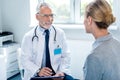 smiling mature male doctor writing in clipboard near female patient Royalty Free Stock Photo