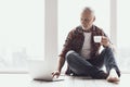 Smiling Mature Man with Beard Using Laptop at Home Royalty Free Stock Photo