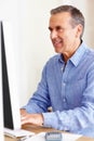 Smiling mature man calculating expenses using computer. Portrait of a smiling mature man calculating expenses using Royalty Free Stock Photo