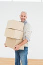 Smiling mature man carrying boxes in a new house