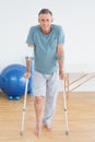 Smiling mature man with crutches at gym hospital Royalty Free Stock Photo