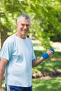 Smiling mature man exercising with dumbbell at park Royalty Free Stock Photo