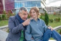 Smiling mature man explaining and showing something to young woman, sit on railing against university building. Family