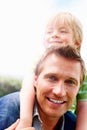 Smiling mature man giving his son piggyback ride. Closeup portrait of a smiling mature man giving his son piggyback ride Royalty Free Stock Photo