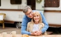 Smiling mature man hugging his beautiful wife in front of camping vehicle outdoors Royalty Free Stock Photo