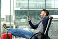 Smiling mature man sitting at train station and using cellphone Royalty Free Stock Photo