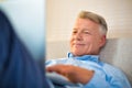 Smiling mature man using laptop while lying on bed at home Royalty Free Stock Photo