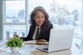 Smiling mature middle aged business woman working on laptop and sitting at desk. Royalty Free Stock Photo