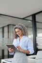 Smiling mature professional business woman using tab computer in office. Royalty Free Stock Photo