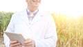 Smiling mature scientist with digital tablet at farm