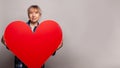 Smiling mature senior woman holding big red heart banner on gray background Royalty Free Stock Photo