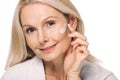 smiling mature woman applying cosmetic cream Royalty Free Stock Photo