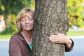 Smiling mature woman arm around tree