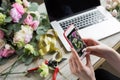 Smiling Mature Woman Florist Small Business Flower Shop Owner. She is using her telephone and laptop to take orders for Royalty Free Stock Photo