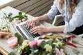 Smiling Mature Woman Florist Small Business Flower Shop Owner. She is using her telephone and laptop to take orders for Royalty Free Stock Photo