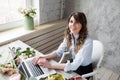 Smiling Mature Woman Florist Small Business Flower Shop Owner. She is using her telephone and laptop to take orders for Royalty Free Stock Photo