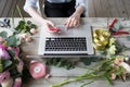 Smiling Mature Woman Florist Small Business Flower Shop Owner. She is using her telephone and laptop to take orders for Royalty Free Stock Photo