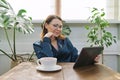 Smiling mature woman having breakfast at home reading digital tablet Royalty Free Stock Photo