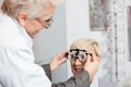 Smiling mature woman having eyesight exam and diopter measurement by a female optometrist at the ophthalmology clinic