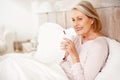 Smiling mature woman having tea or coffee in bed. Portrait of a smiling mature woman having tea or coffee in bed. Royalty Free Stock Photo