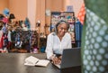 Smiling mature woman in her fabric shop using a laptop Royalty Free Stock Photo